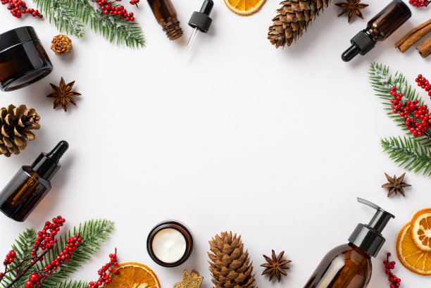 冬季护肤理念。化妆品瓶的俯视图照片槲寄生浆果松果云杉树枝干橙片和八角在孤立的白色背景与中间的复制空间图片下载