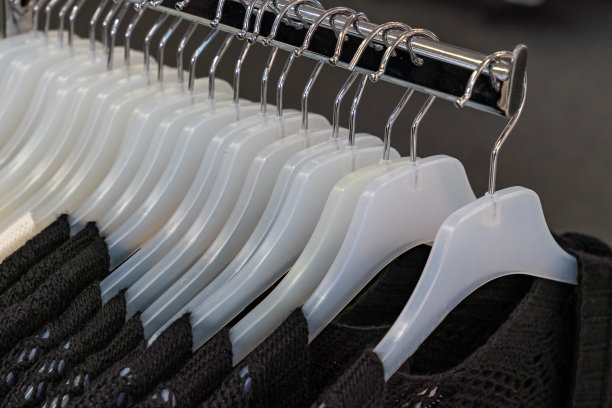 商店里的一排白色塑料衣架，上面挂着一件棕色针织夹克。图片下载