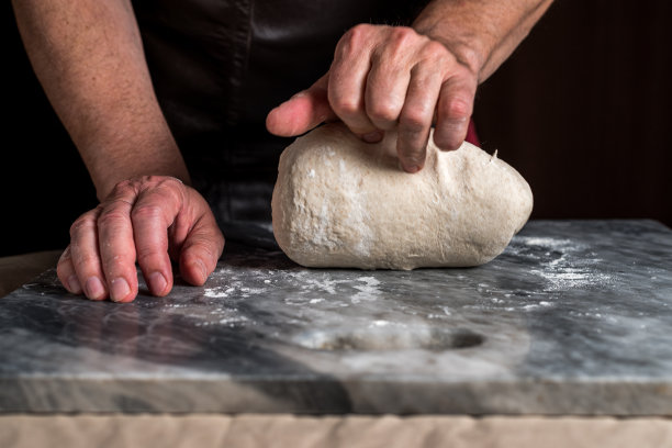 男子准备披萨，面团放在大理石桌上。图片下载