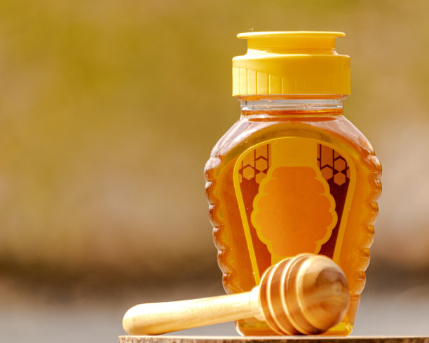 蜂蜜装在模糊背景的塑料瓶里图片下载