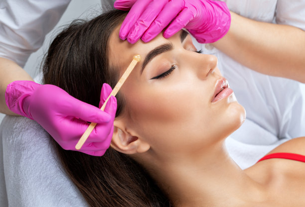 化妆师做面部除毛手术。美丽的女孩在她的眉毛上化了永久的妆。化妆师给眉毛做持久的造型图片下载