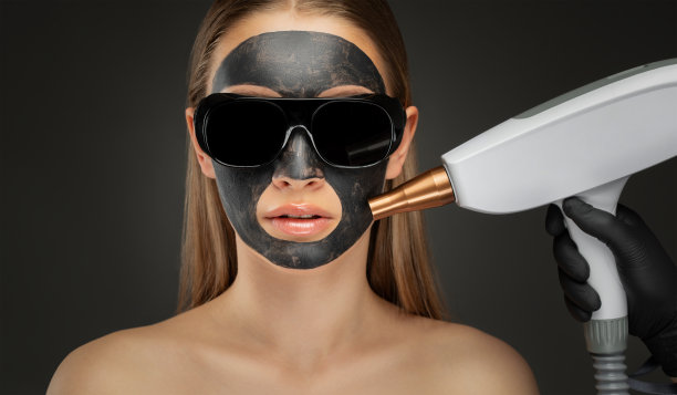 美容院给漂亮女孩做碳脱皮手术。她脸上戴着一个黑色的面具。硬件美容治疗。图片下载