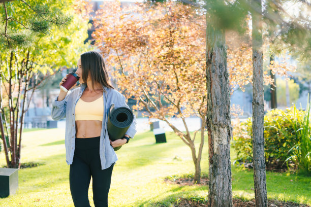 女子在公园晨练后回家，愉快地喝着咖啡。积极健康的生活方式。户外生活方式。健康的女人。健康的生活方式,运动。夏天休息。人们的生活方式。健身锻炼。图片下载
