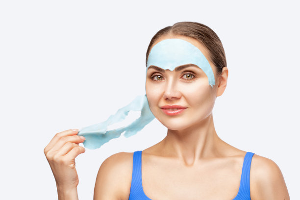 一位美容师为一位女士制作了一款海藻酸盐蓝色面膜，使她的皮肤焕发活力。面部和身体问题皮肤的美容治疗。图片下载