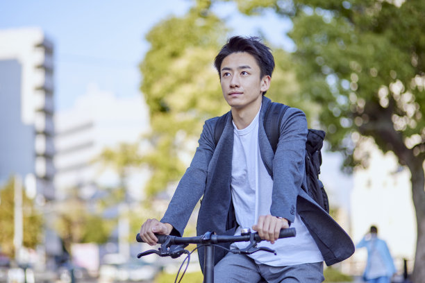 年轻的日本男子穿着夹克骑自行车图片下载