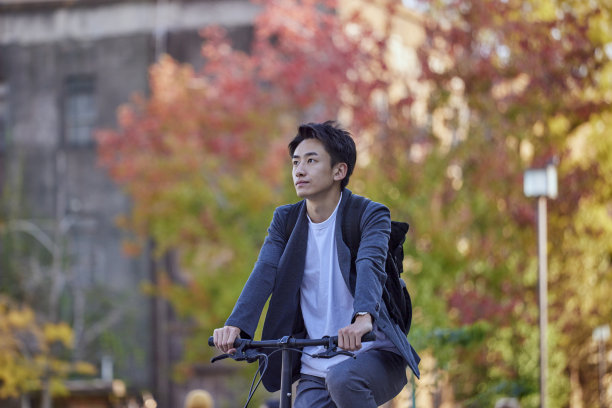 年轻的日本男子穿着夹克骑自行车图片下载