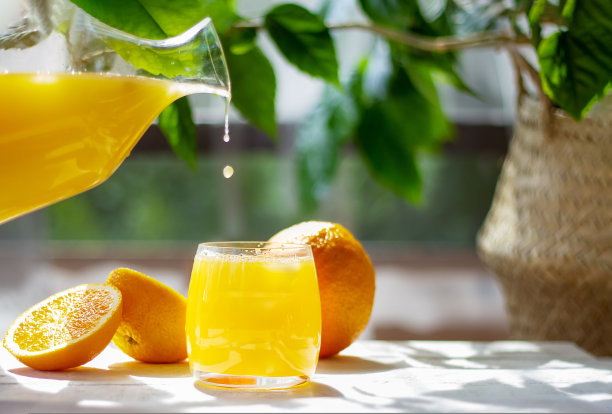 橙汁从大水罐中滴入玻璃杯。健康的柑橘类饮料。夏天新鲜概念。图片下载