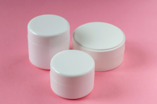 粉色背景上的三个白色化妆罐图片下载