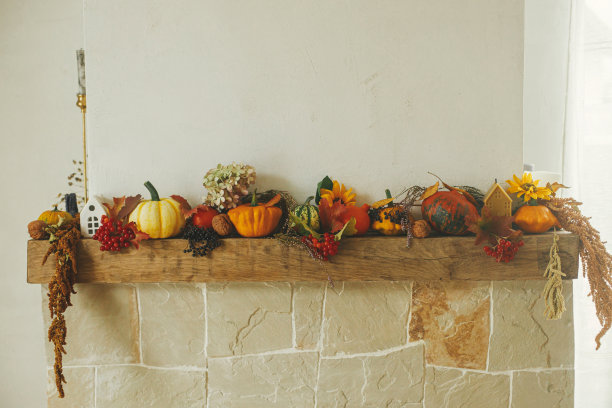 乡村房间壁炉上的秋季装饰。时尚的南瓜，花，浆果，坚果，蜡烛在质朴的木头上时尚的壁炉。农舍收获，秋天装饰。感恩节和万圣节快乐图片下载