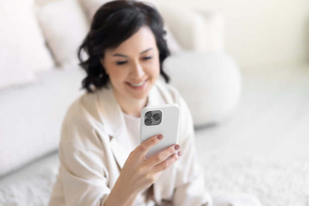 现代智能手机机身上的三个摄像头的特写。快乐的中年妇女看着模糊的背景智能手机屏幕。小工具。图片下载