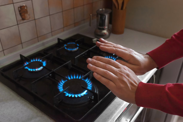 一个男人的手靠近煤气炉的特写。冷供暖季节图片下载