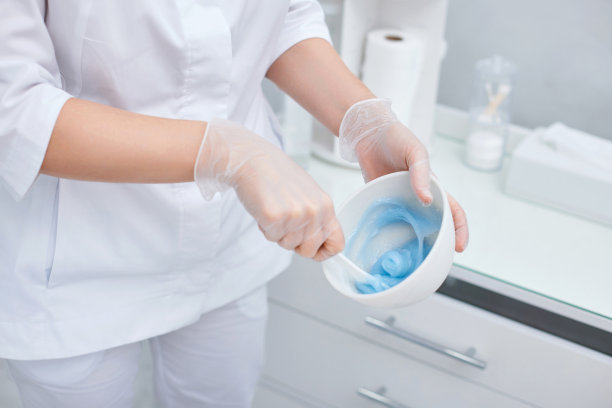 美容师手拿蓝色藻酸盐面膜碗。图片下载