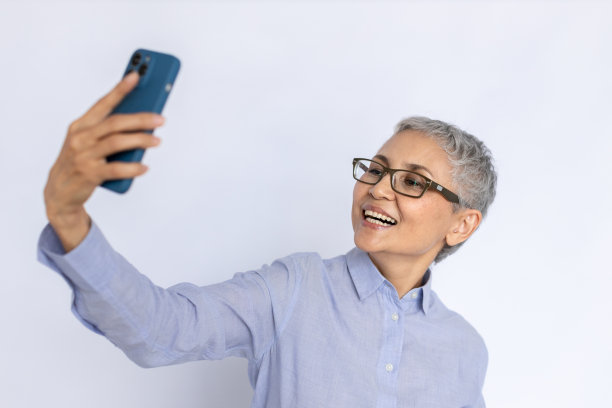 欢快的老年妇女用智能手机自拍的肖像图片下载