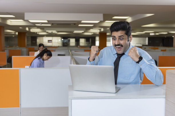 商人使用笔记本电脑，在办公室庆祝成功。图片下载