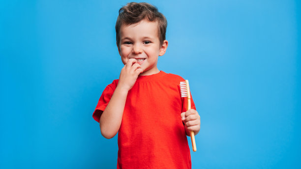 牙齿健康的微笑男孩在蓝色的孤立背景下用牙刷刷牙。口腔卫生。图片下载