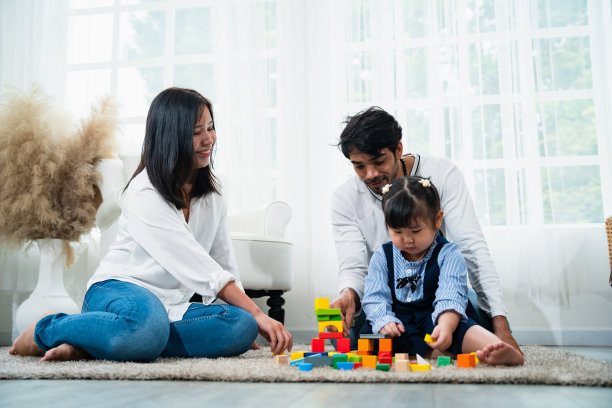 夫妇和可爱的女儿玩彩色几何形状玩具以促进她们的发展图片下载