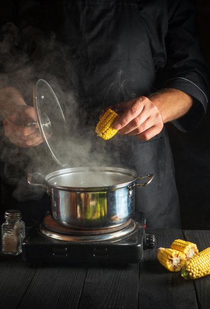 专业厨师做玉米。特写的厨师是在餐厅厨房做饭的手。图片下载