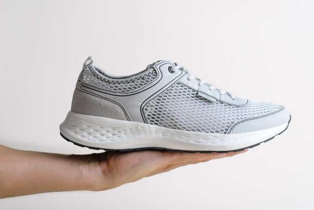 人的手显示新的时尚运动鞋在光背景。单夏日靴在手臂上，特写，侧视图图片下载