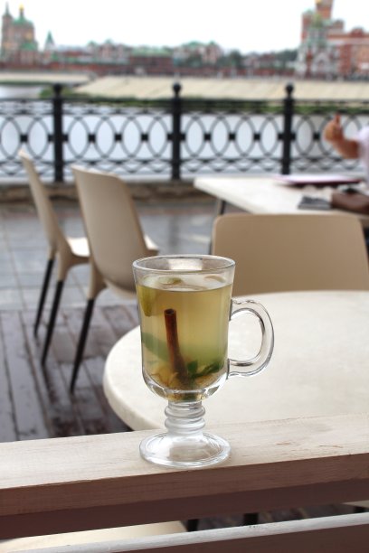 在夏日咖啡馆的阳台上，栏杆上有一个杯子，里面盛着美味的茶。图片下载