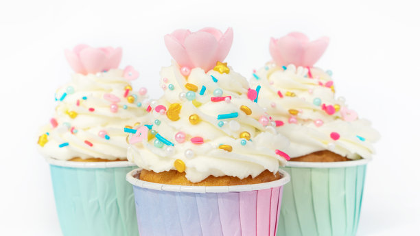 奶油纸杯蛋糕，白色背景上有金色的特写。节日甜点与华夫饼花装饰优雅的婚礼，周年纪念，儿童聚会。图片下载