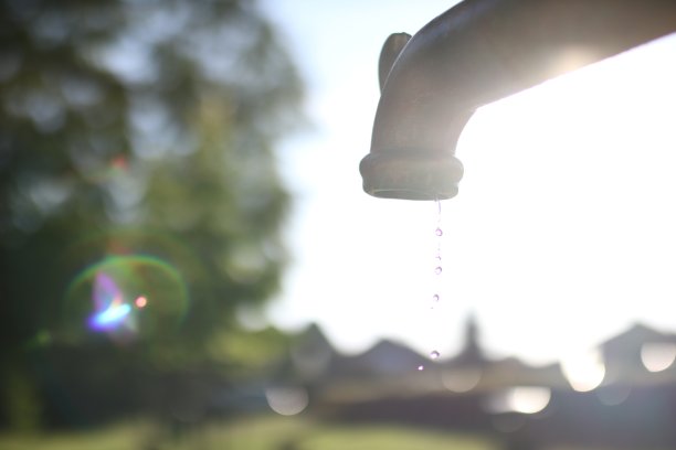 特写景观镜头滴水在水龙头与模糊的背景图片下载