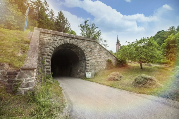 在一个晴朗的日子里，一个被树木和草地包围的古老隧道的入口令人惊叹的照片图片下载