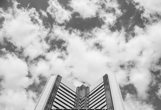 以多云的天空为背景的建筑物上部的灰度照片图片下载