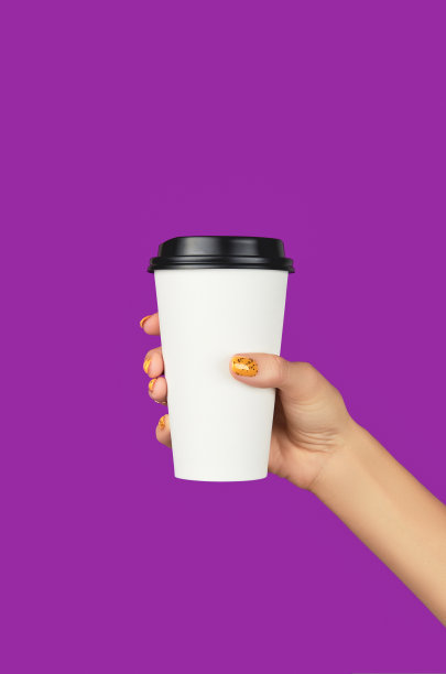 女人的手与时髦的橙色美甲拿纸杯在紫色的背景图片下载