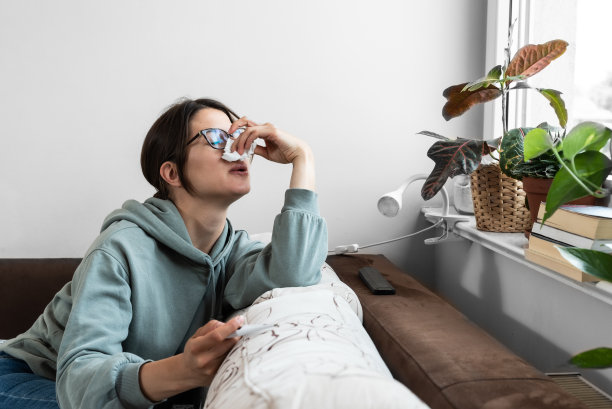 年轻沮丧的生病的妇女生病的普通感冒和流感病毒测量她的体温，感觉痛苦和虚弱。商务妇女因病不能上班。图片下载
