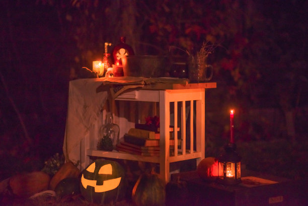 万圣节快乐，在花园里的桌子上雕刻南瓜。幸福的家庭为万圣节做准备。图片下载