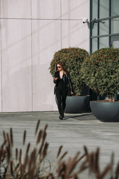 时尚的年轻女子长发，穿着结实的长袖紧身连体衣，黑色皮夹克和光滑的厚底靴图片下载