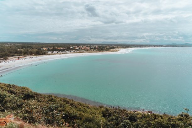 在多云的天空下，被绿色植物覆盖的岛屿包围的海洋景观图片下载