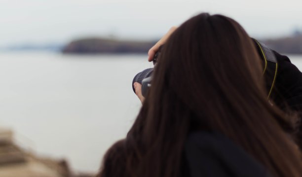 浅聚焦从后面拍摄的一位正在拍照的女性图片下载