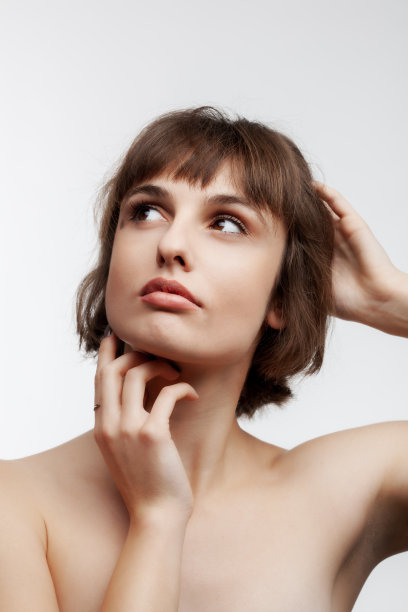 工作室肖像的一个美丽的黑发女孩短发向上看孤立的白色背景。图片下载