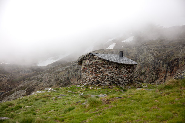 在一个雾天，山上的石头房子和岩石和草，令人惊叹的照片图片下载