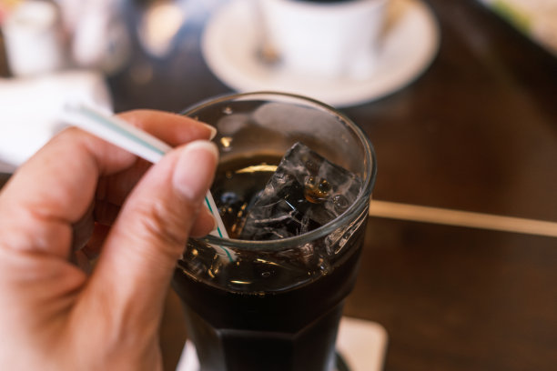 一个女人正在喝加冰块的冰咖啡。图片下载