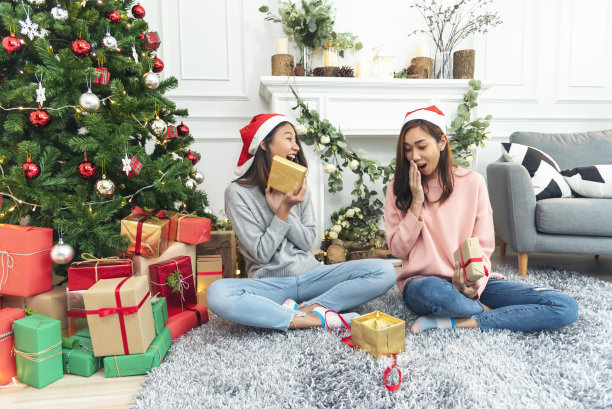 两个女人姐弟用手装饰圣诞树红球、小玩意、雪花。双手捧着红球装饰。亚洲女性朋友装饰小玩意球圣诞树圣诞假期图片下载