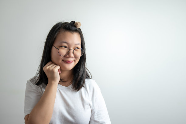 亚洲玻璃女人在工作室的灯光下摸着她的脸颊，想着一些事情。图片下载