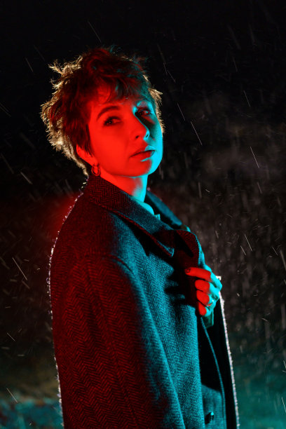 被冻住的白人妇女，披着外套，站在夜晚的街道上摆姿势图片下载