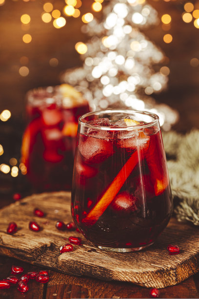 一杯以圣诞装饰和灯光为背景的橙色石榴鸡尾酒。节日的冬季饮料垂直照片图片下载
