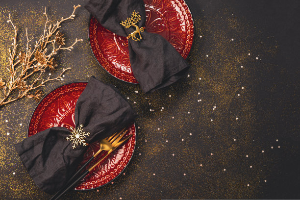 新年和圣诞节餐桌布置概念。红色的空盘子与亚麻餐巾在节日黑色圣诞桌面的顶部视图，复制空间的文字图片下载