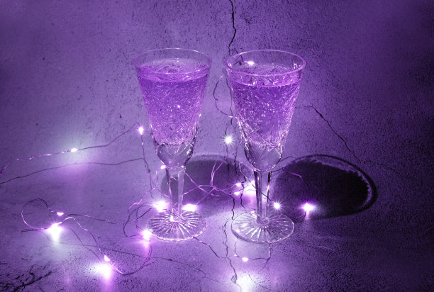 两个香槟酒杯在黑暗中与紫罗兰色效果的岩石背景图片下载
