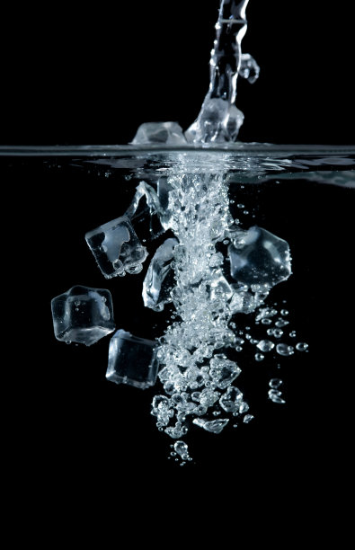 将冰块放入水中，黑色背景上有气泡图片下载