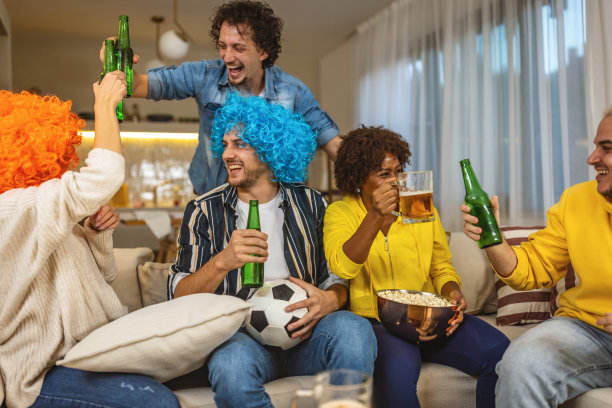一群在电视上看足球比赛的朋友庆祝他们球队的胜利图片下载