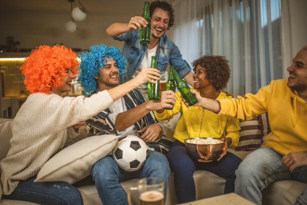 一群在电视上看足球比赛的朋友庆祝他们球队的胜利图片下载