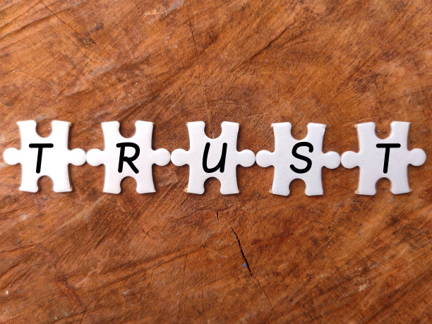 顶部视图白色谜题与字信托在木制背景。图片下载