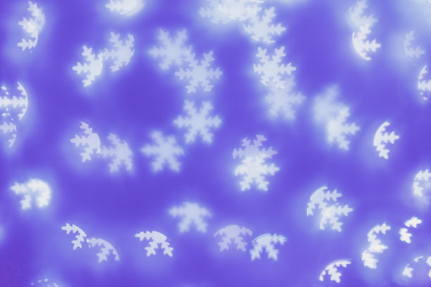 散景如灯白色雪花在蓝紫色的背景，抽象的寒假墙纸与模糊的图案。圣诞节或新年的抽象图像作为背景，美学模糊背景图片下载