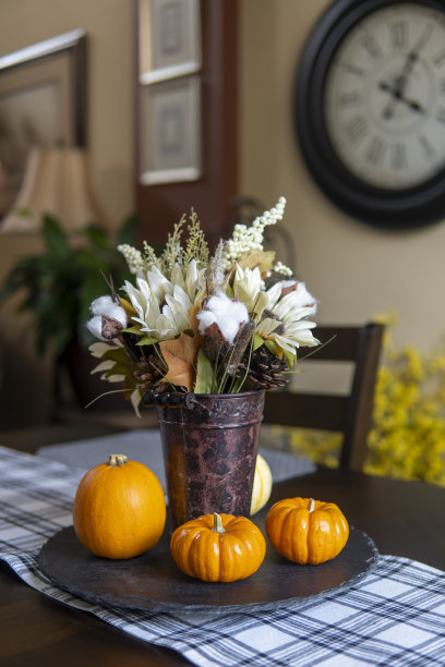客厅的桌子上放着一束人造花和迷你南瓜。感恩节的概念图片下载