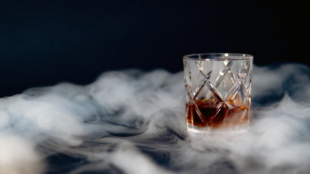 一杯威士忌放在黑色背景下烟雾弥漫的桌子上图片下载