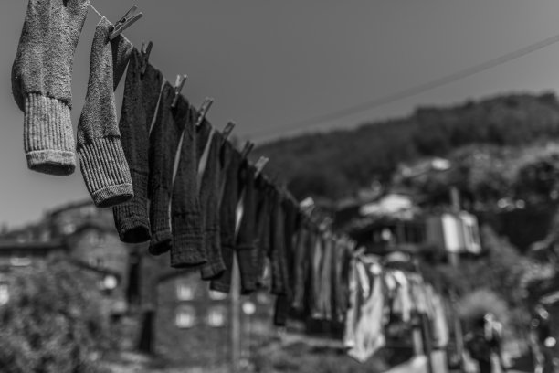 在阳光下被群山环绕的田野里，洗过的袜子在一条线上的灰垢图片下载